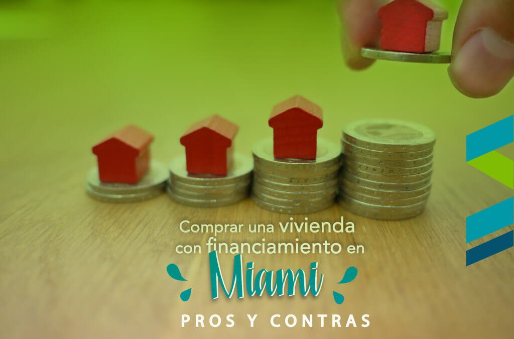 Casas rojas miniatura sobre pilas de monedas representando pros y contras de comprar vivienda con financiamiento en Miami
