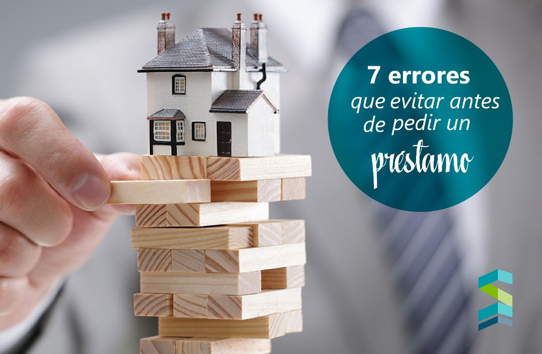 Modelo de casa en equilibrio sobre bloques de madera representando errores que evitar antes de pedir un prestamo hipotecario